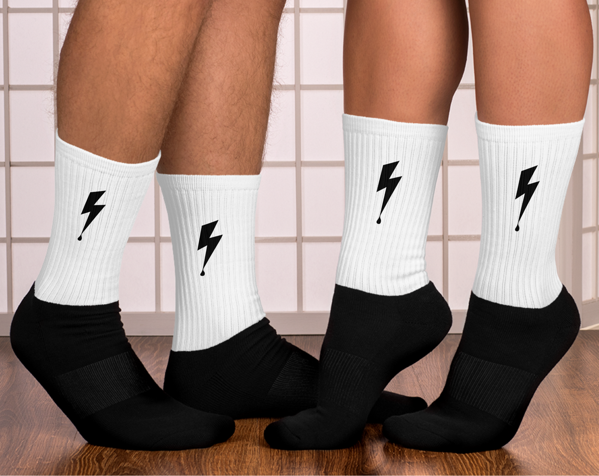 White socks with black lightning bolt designs worn by two people on a tiled floor. 